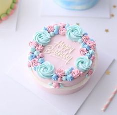 a birthday cake decorated with pastel blue and pink icing on a white table