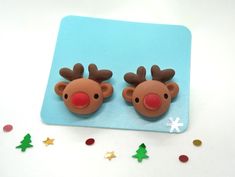 two brown reindeer head earrings sitting on top of a blue plate next to confetti