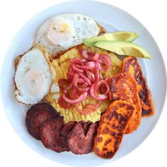 a white plate topped with eggs, sausage and avocado next to other foods