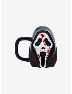 a black and white mug with a red mask on it's face in the air