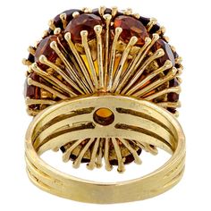 This is part of Chairish’s Fine Jewelry assortment.  This mid-century cocktail ring is a unique blend of design and craftsmanship. Its distinctive three-dimensional Bombay or Dome-style design is a testament to its exclusivity, sure to captivate and intrigue. The ring is meticulously crafted from 18kt yellow gold, renowned for its durability and luster.  At the center of the ring sits a large oval brilliant-cut citrine measuring an impressive 11.4mm length X 9.4mm width. The citrine is a beautiful burnt orange color. It is surrounded by ten (10) smaller oval brilliant-cut citrines measuring 7 x 5 mm, and ten (10) round brilliant-cut citrines measuring 4.5 mm also add to the ring's overall radiance and beauty.  All the gemstones are prong-set in the mount, ensuring they are securely held. I Yellow Gold Cocktail Ring, Gold Cocktail Ring, Burnt Orange Color, Gold Cocktail, Cocktail Ring, Cocktail Rings, Style Design, Round Brilliant, Burnt Orange