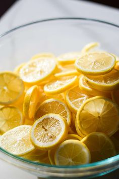 a glass bowl filled with sliced lemons on top of a table