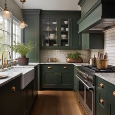 a kitchen with green cabinets and marble counter tops, gold pulls on the faucets