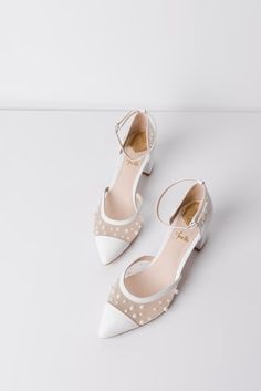 two pairs of white shoes with polka dots on the toes and heels, one in high heel