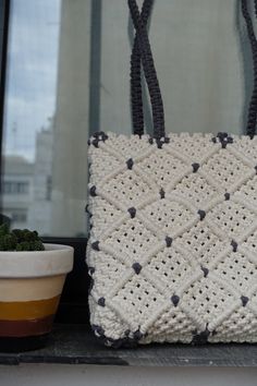 a crocheted bag sitting on top of a window sill next to a potted plant