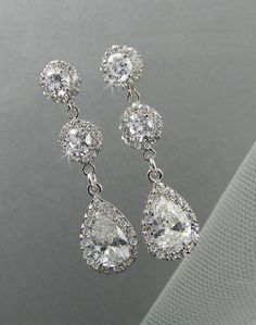 two pairs of diamond earrings on a white cloth