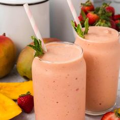 two glasses filled with smoothie next to bananas and strawberries