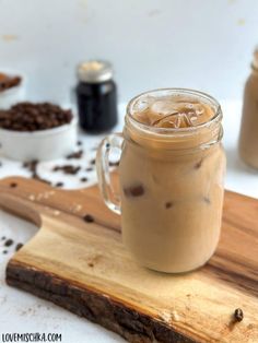 there is a drink in a mason jar on a cutting board next to some coffee beans