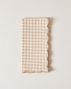 a beige and white checkered napkin with scalloped edges on a white background