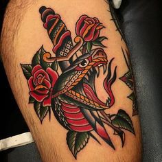 a close up of a tattoo on a person's leg with roses and dagger