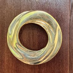 a close up of a metal object on a wooden surface with wood grained background