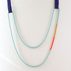 two necklaces are hanging on a white surface