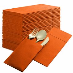 a stack of orange napkins with silverware on top