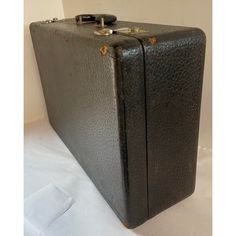 an old black suitcase sitting on top of a bed