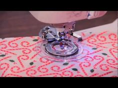 a sewing machine is on top of a table with a red and white cloth behind it