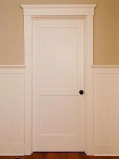 an empty room with two white doors and wood floors