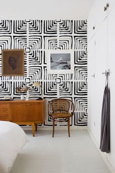 a bedroom with black and white wallpaper, two chairs and a desk in front of the bed