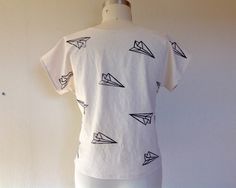 "Simple, boxy top made of 100% linen in white that has been block printed with a paper airplanes in black ink. Currently available in XS, S, M, L & XL Please choose size at checkout Size XS measures 37\" around the bust 38\" around the hem 21\" long Size Small measures 39\" around the bust 41\" around the hem 22\" from shoulder to hem Size Medium measures 42\" around the bust 44\" around the hem 23\" from shoulder to hem Size Large measures 45\" around the bust 47\" around the hem 25\" from White Hand Printed Crew Neck Top, White Printed Everyday Tops, White Printed Tops For Everyday, Everyday White Printed Tops, Casual White Hand-printed Top, White Hand Printed Short Sleeve Tops, Airplane Print, Boxy Top, Linen Tank Top