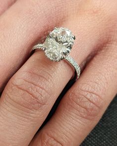 a woman's hand with a diamond ring on top of her finger and an engagement band