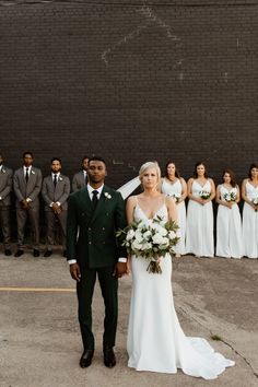 a bride and groom standing in front of their wedding party