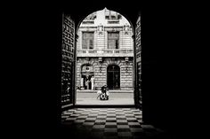 black and white photograph of people sitting in front of an arched entrance to a building