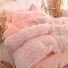 a bed with pink fluffy comforters and pillows