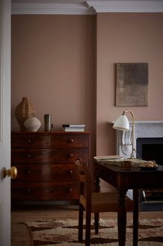 a living room with a dresser, chair and table in front of a fire place