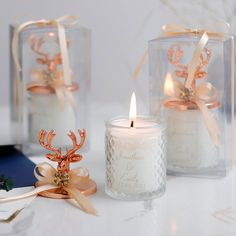 two candles are sitting next to each other on a table with ribbons and bows around them