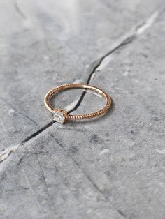 a gold ring sitting on top of a gray rock with a diamond in the middle