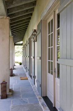 an empty walkway between two buildings with doors and lanterns on either side of the building