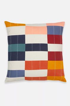 an orange, blue and red patchwork pillow on a white background