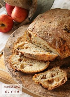 sliced loaf of bread sitting on top of a wooden cutting board next to an apple