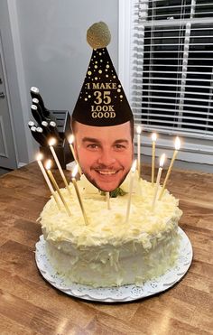 a man wearing a birthday hat with candles sticking out of his face on top of a cake