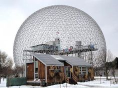 a large metal ball sitting in the middle of a snow covered field next to a building