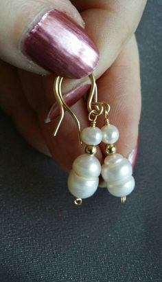 "Two genuine cultured pearls in creamy white dangle about 3/4\" from handcrafted 14/20 gold filled earwires in these classically elegant earrings.  This style is easy to wear and comfortable. Pearls are associated with the sea, feminity, the moon, purity, and all that is precious. The gleaming gold setting adds balance with solar, energizing, traditionally masculine associations.   Classically beautiful, these earrings are also quite versatile.  They will go well with business wear, evening wear Pearl White Dangle Earrings, Feminine Style, Gold-tone Pearl Drop Dangle Earrings, Luxury Pearl Drop Gold-tone Earrings, Elegant Shell-shaped Earrings With Pearl Charm, White Pearl Drop Shell-shaped Earrings, Business Wear, Earrings Round, Round Earrings, Gold Set