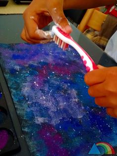 a person holding a toothbrush in their right hand and painting on the other side