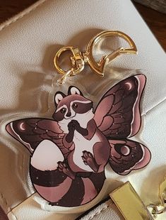 a raccoon keychain on top of a white purse