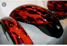 three red and black glass vases sitting on top of a white cloth covered table