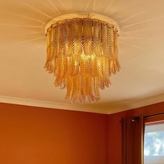 a chandelier hanging from the ceiling in a room with orange walls and curtains