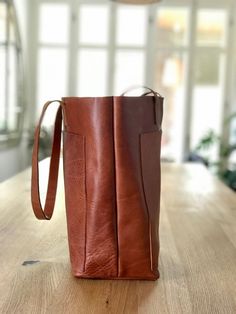 "Oversized leather bag, made with the highest quality veg tanned leather. Its clean, design and large size makes this beautiful bag a versatile bag for your daily day or traveling, allowing to carrying lots of things. Features: - Highest quality Full Grain Veg Tanned leather - Aprox Measures: 14-17.5 in wide (35-45 cm) (bottom and aprox top width) - easily fits a 15\" laptop 14 in high (36 cm) 6 in deep (15 cm) Big outside pocket (14\"x10\") or (36x25 cm): This pocket is big enough for a 13\" la Brown Bucket Bag With Pockets For Travel, Brown Travel Bucket Bag With Pockets, Brown Bucket Bag With Double Handle And Pockets, Brown Bucket Bag With Pockets, Leather Bucket Bag Tote With Pockets, Leather Bucket Bag With Pockets For Daily Use, Leather-backed Bucket Bag, Large Leather Bag, Oversized Bag