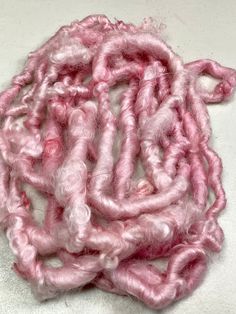 pink and white yarn is on top of a white surface with small holes in the middle