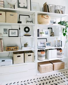 a white bookcase filled with lots of books and baskets next to a wall full of pictures