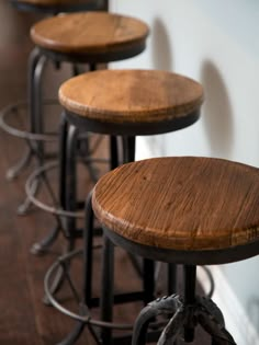 three wooden stools sitting next to each other on top of a hard wood floor