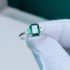 an emerald ring with three diamonds on it