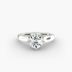 a white gold engagement ring with a round brilliant cut diamond in the center, on a plain surface