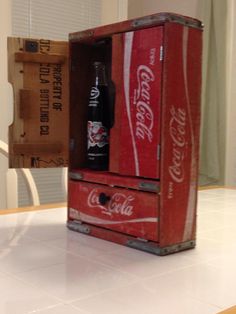 an old coca - cola cooler sitting on top of a counter next to a box