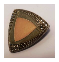 Beautiful enameled brooch in a classic 40s or 50s style. A double triangle with rounded edges in almond green and matte gold or pinkish beige tones framed on three sides by a throw of transparent rhinestones A very fine gold dusting over the entire surface gives a discreet and elegant luminosity Marked France on the back followed by a logo that I was unable to identify Safety closure Dimensions 35/35 millimeters Unique, antique, vintage piece in perfect condition. Free delivery with code DORA194 Pinkish Beige, Double Triangle, Jewelry Brooch, Beige Tones, Vintage Fine Jewelry, 50s Style, Tie Accessories, Gold Enamel, Jewelry Vintage