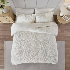 an aerial view of a bed with white comforter and pillows