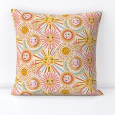 a decorative pillow with sun and moon faces on the front, sitting on a white surface