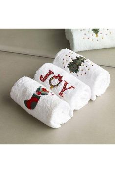 three white towels with embroidered words and christmas decorations on them, sitting next to each other